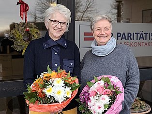 2 FRauen stehen vor einem Gebäude und lächeln in die Kamera