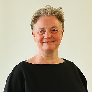 Eine Frau mit kurzen Haaren lächelt in die Kamera