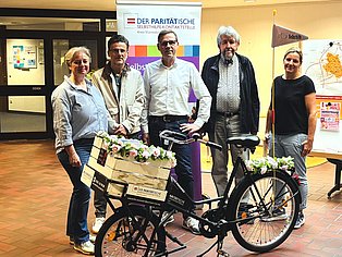 5 Menschen stehen um ein Fahrrad und schauen in die Kamera