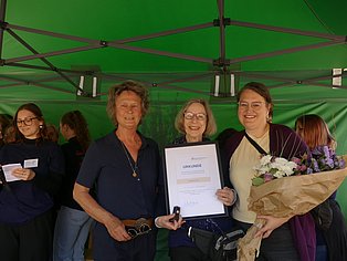 3 Frauen stehen zusammen udn lächeln in die Kamera
