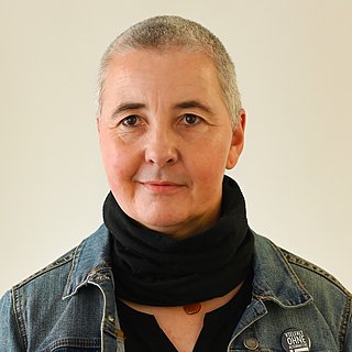 Eine Frau mit kurzen Haaren lächelt in die Kamera