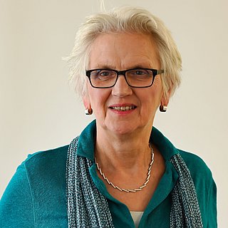 Eine Frau mit kurzen Haaren lächelt in die Kamera